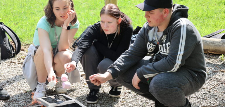 Future Skills students cooking marshmallows over barbecue out side Dalehead courts