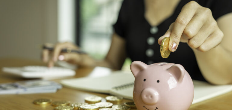 A female puts a coin into the piggy bank. And calculate income Monthly expenditures For family saving money, saving ideas and money saving.